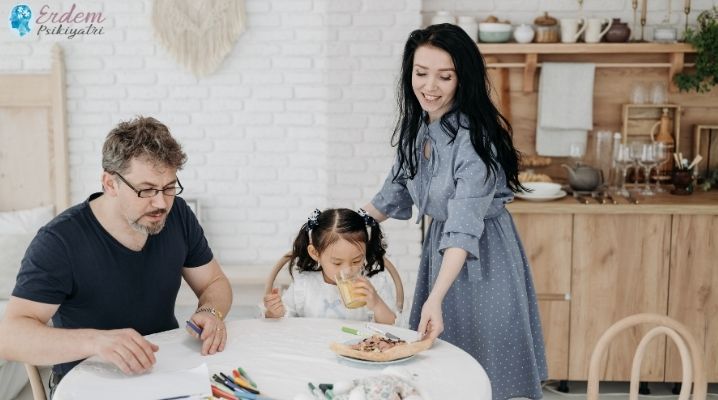 Koruyucu ailesi olan bir kız çocuğu ve anne ve babası ile yemek yiyor.