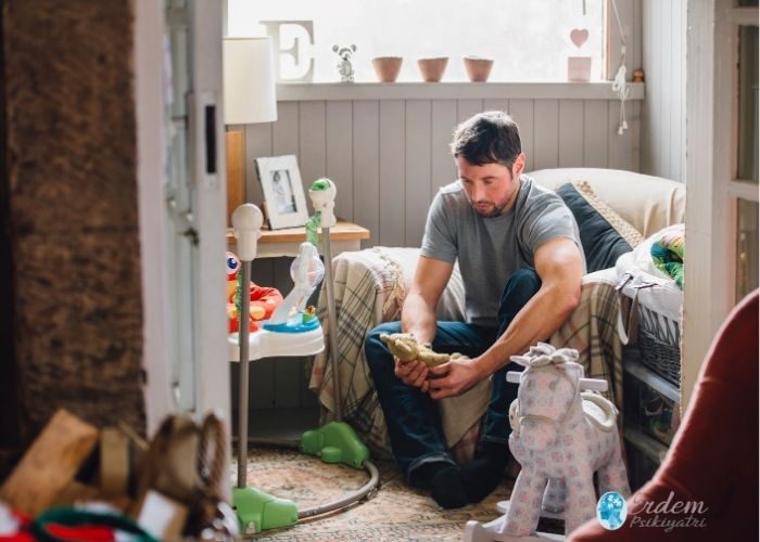 Yas süreci geçiren erkek bir birey yatak üzerinden düşünceli oturmakta