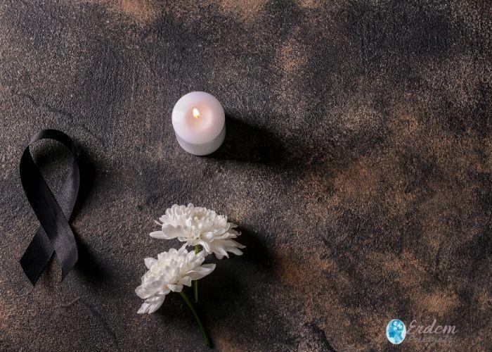 Siyah kurdele, beyaz çiçek ve yanan mum – yas tutan kişiye destek temalı görsel